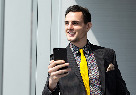 A young professional goes online on his phone to look for information about retirement savings.