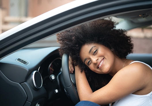 A Namibian woman leans her head against the steering wheel of her vehicle.