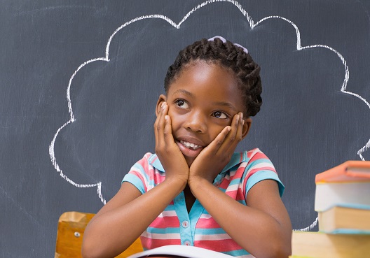 A young girl holds her face in both hands and daydreams.