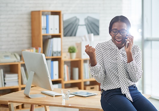 A female employee wearing a black and white dotted blouse chats on the phone. 