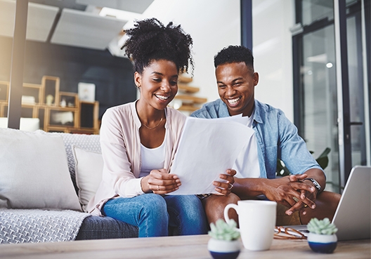A couple sit together and look at quotes for a combined home and car insurance policy.
