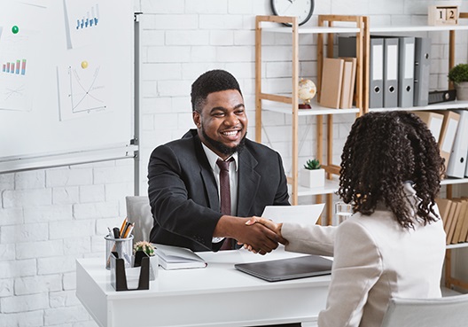 A male Old Mutual employee shakes the hand of a female customer. 